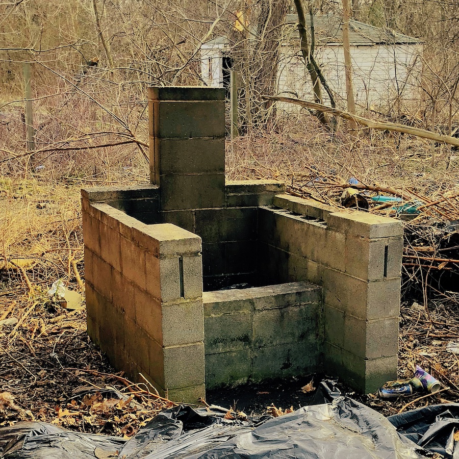 Photograph of a cinder block grill area. Neighbors garage is visible in the background.